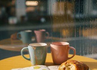 Mental Health Coaching: 7 Benefits You Didn’t Know About A blurry phone photo of a coffee shop table with chipped mugs, a stained notebook with smiley doodles, a crumbling croissant, and a rainy window.