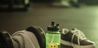 Why Hiring a Fitness Coach Near You Will Jumpstart Your Goals A sweaty gym towel on a dumbbell, a water bottle with a sticker, a crumpled workout plan, and a sneaker on a gym floor