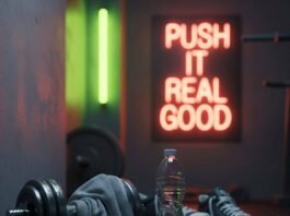 Top Fitness Classes Near Me: Boost Your Health with These Popular Options A blurry gym corner with a sweaty towel on a dumbbell, a water bottle, mismatched sneakers, and a neon sign saying "Push It Real Good."