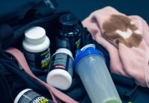 Fitness Supplements Near Me Can Help You Reach Your Goals Faster A gym bag spills supplement bottles, a shaker, and a resistance band, with a coffee-stained towel in the background.