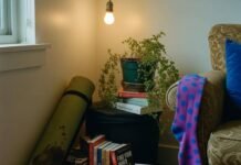 Holistic Health and Wellness: 10 Steps to Start Living Your Best Life A dimly lit corner of a cluttered apartment features a rolled-up, coffee-stained yoga mat, stacks of self-help books, a drooping fern, and a bright purple polka-dot sock hanging from an armchair.