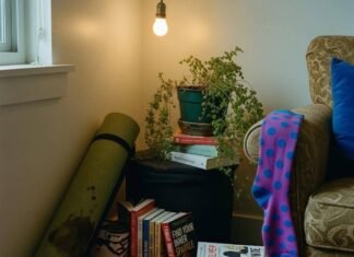 Holistic Health and Wellness: 10 Steps to Start Living Your Best Life A dimly lit corner of a cluttered apartment features a rolled-up, coffee-stained yoga mat, stacks of self-help books, a drooping fern, and a bright purple polka-dot sock hanging from an armchair.