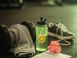 Why Hiring a Fitness Coach Near You Will Jumpstart Your Goals A sweaty gym towel on a dumbbell, a water bottle with a sticker, a crumpled workout plan, and a sneaker on a gym floor