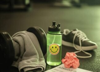 Why Hiring a Fitness Coach Near You Will Jumpstart Your Goals A sweaty gym towel on a dumbbell, a water bottle with a sticker, a crumpled workout plan, and a sneaker on a gym floor